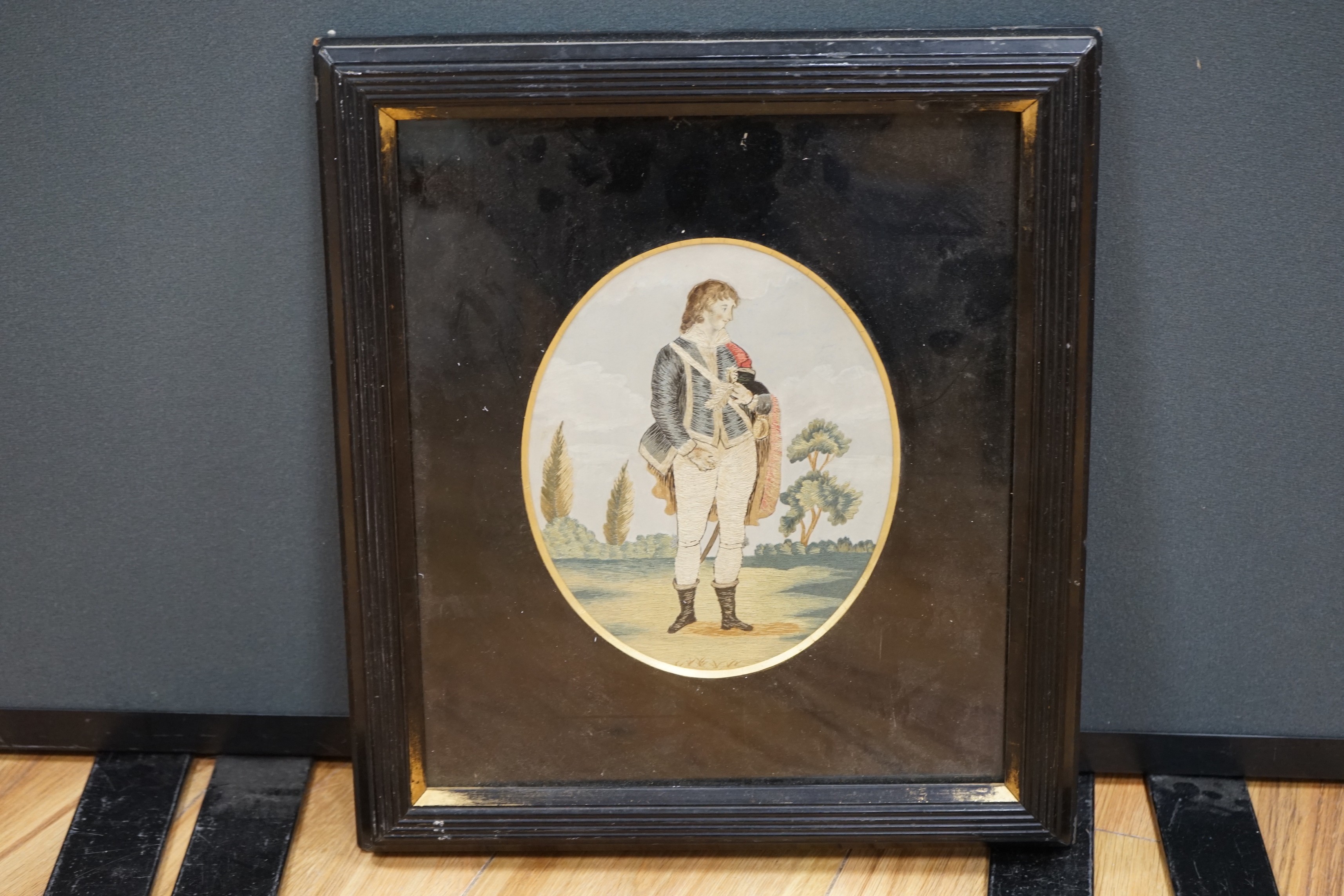 An oval Regency silkwork picture of a gentleman amongst landscape in glazed frame, 20 x 17cm